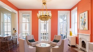 Een woonkamer met een ronde salontafel, twee fauteuils, een kroonluchter en een open haard.