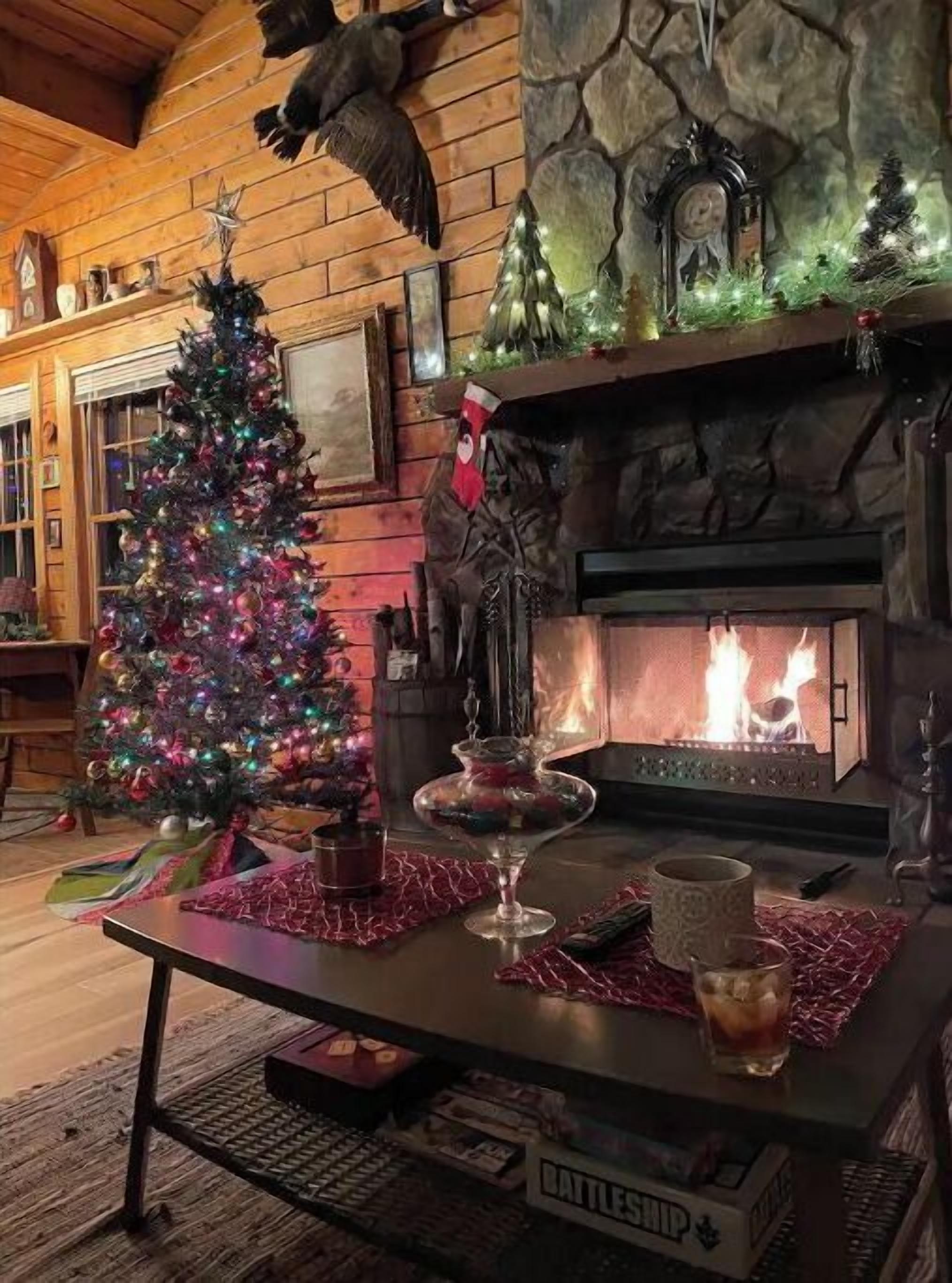 Un salon chaleureux avec une cheminée, un sapin de Noël et un mur en pierre.