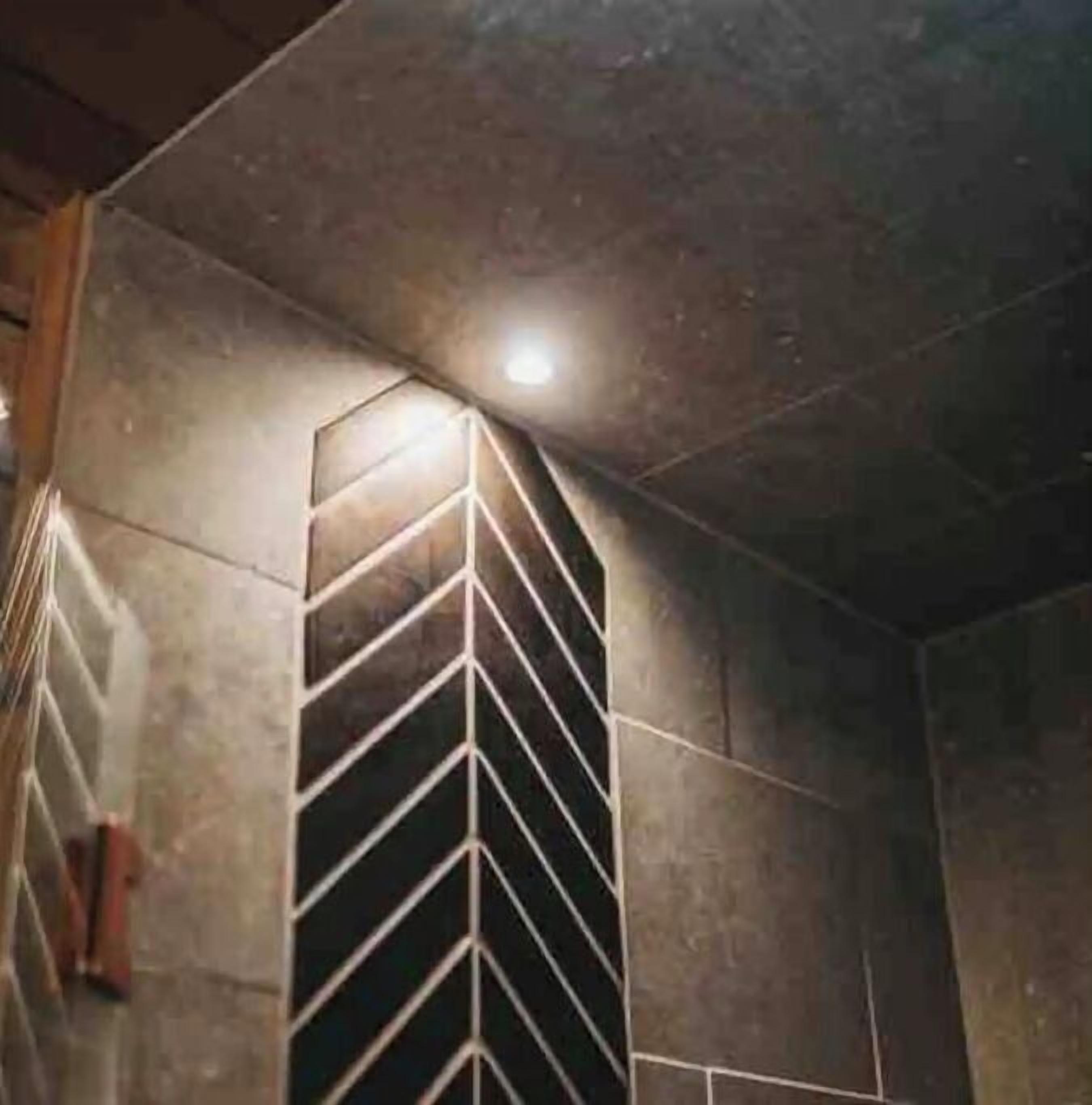 Una habitación con un papel tapiz de diseño geométrico, una lámpara empotrada en el techo y un marco de puerta visible.