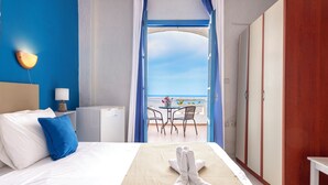 A hotel room with a bed, a table with chairs, a view of the sea, and a balcony with a table and chairs. - Bluu Bahari EE (Karpathos)