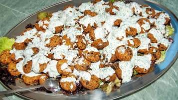 Um prato de bolinhos de falafel com molho branco, servido em uma chapa de metal.