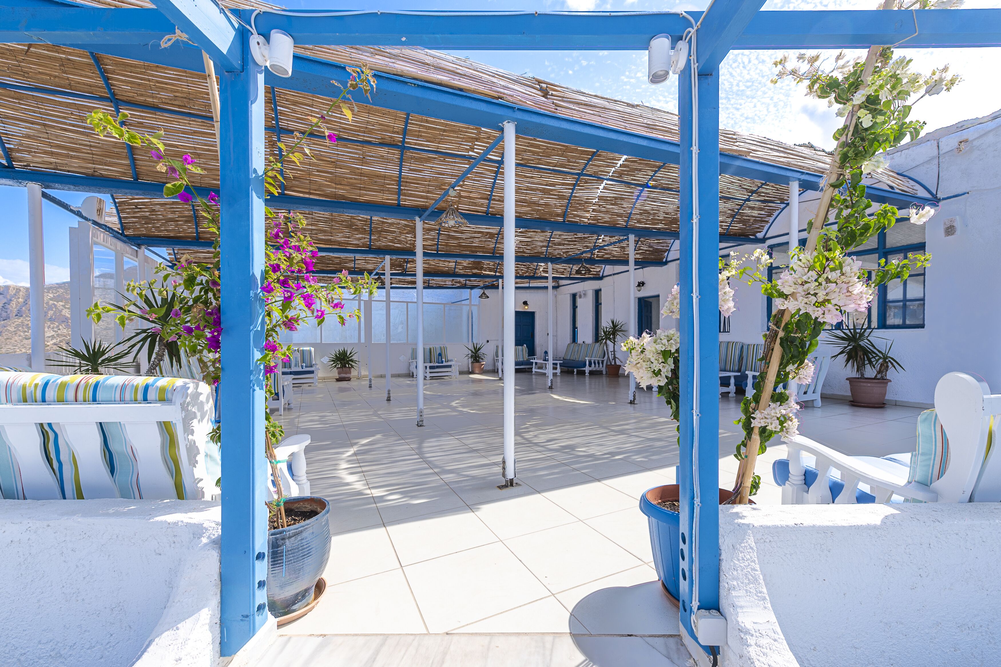 A covered outdoor area with white furniture and potted plants.