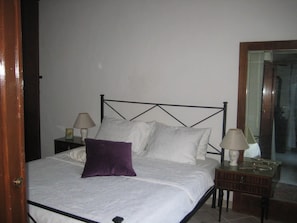 A bed with a metal frame, two bedside tables with lamps, and a wooden nightstand.