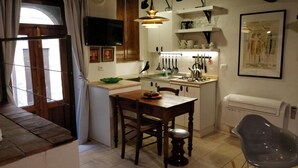 A cozy kitchen with wooden cabinets, a dining table, and a modern chair. - Casa Messi - Casa Messi a Vicolo Della Rivolta 25 Apt 5 (Pitigliano)