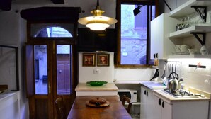 A compact kitchen with a wooden dining table, a green bowl, and a kettle on the counter. - Casa Messi - Casa Messi a Vicolo Della Rivolta 25 Apt 5 (Pitigliano)