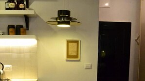 A small kitchen with a wooden table and chairs, a gas stove, and a hanging light fixture. - Casa Messi - Casa Messi a Vicolo Della Rivolta 31 Apt 2 (Pitigliano)