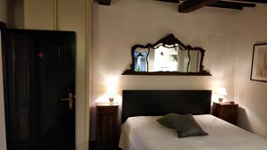 A bedroom with a bed, two bedside lamps, a mirror, and a door. - Casa Messi - Casa Messi a Vicolo Della Rivolta 31 Apt 4 (Pitigliano)