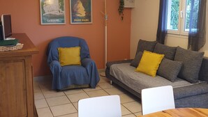 Un salon avec un canapé, un fauteuil, une table à manger et des affiches accrochées au mur.