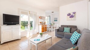 Ein modernes Wohnzimmer mit einer grauen Couch, einem weißen Couchtisch und einem Flachbildfernseher.