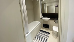 A modern bathroom with a bathtub, a sink, and a shower curtain.