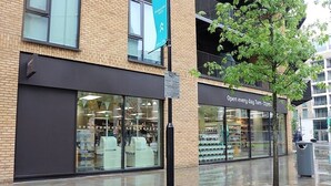 A modern building with large windows and a sign indicating it is open every day from 7am to 11pm.