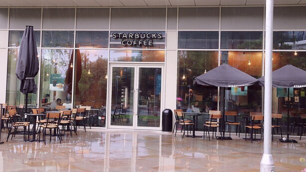 A Starbucks Coffee with outdoor seating and a glass storefront.