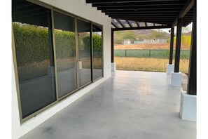 Relax in a serene outdoor space with a modern design, featuring a concrete floor and glass doors leading to the surrounding landscape.