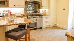 Una cocina con encimera de granito, electrodomésticos de acero inoxidable y armarios blancos.