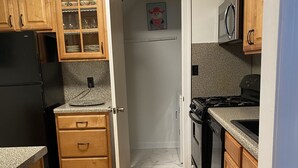 A compact kitchen with wooden cabinets, a refrigerator, a microwave, and a stove.