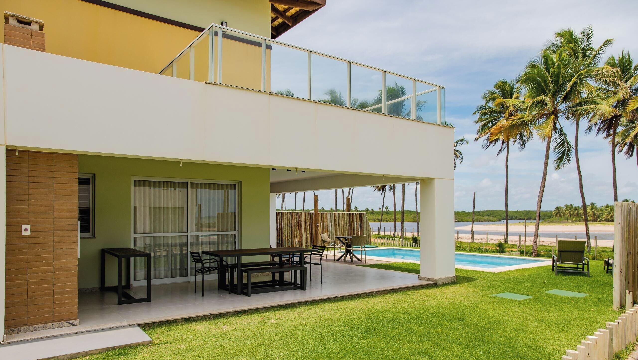 A two-story building with a balcony, a pool, and a grassy lawn.