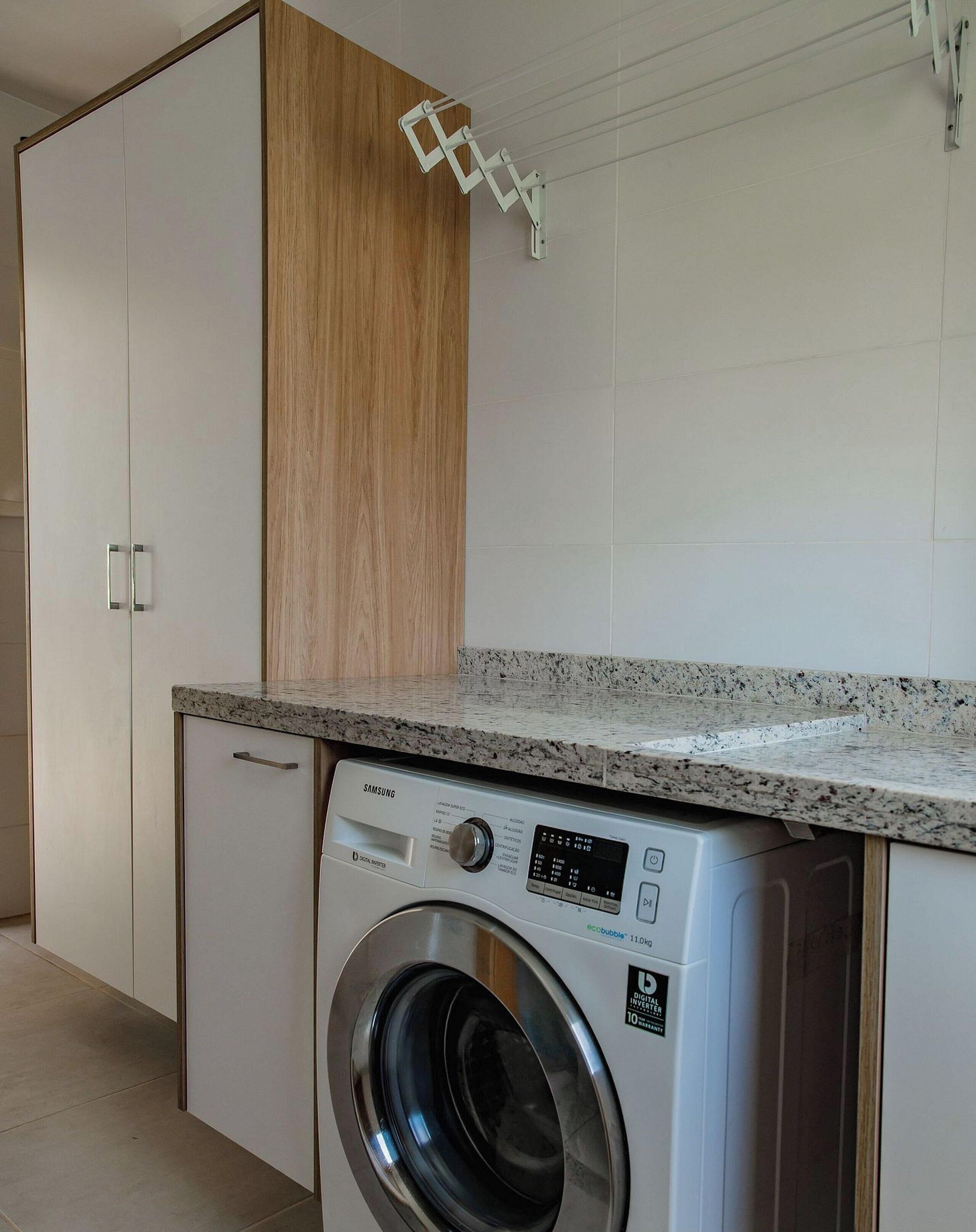 A compact kitchen with a built-in washing machine, wooden cabinets, and a granite countertop.