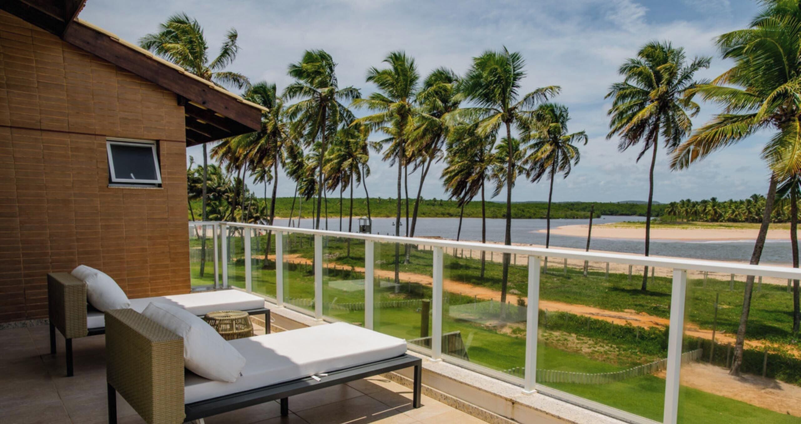 A balcony with a view of a beach and palm trees.