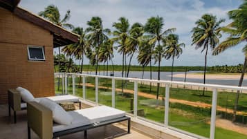A balcony with a view of a beach and palm trees.
