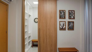A hallway with a wooden door, a bench, and four framed artworks on the wall. - Ponta de Inhambupe Residences (Esplanada)