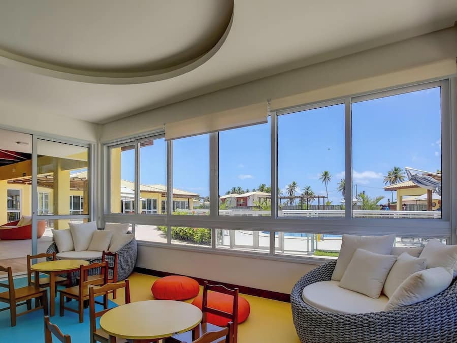 A spacious indoor area with large windows, seating arrangements, and a view of the outside.