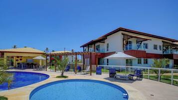 Um resort com piscina, área de estar externa e um prédio de dois andares com varandas.