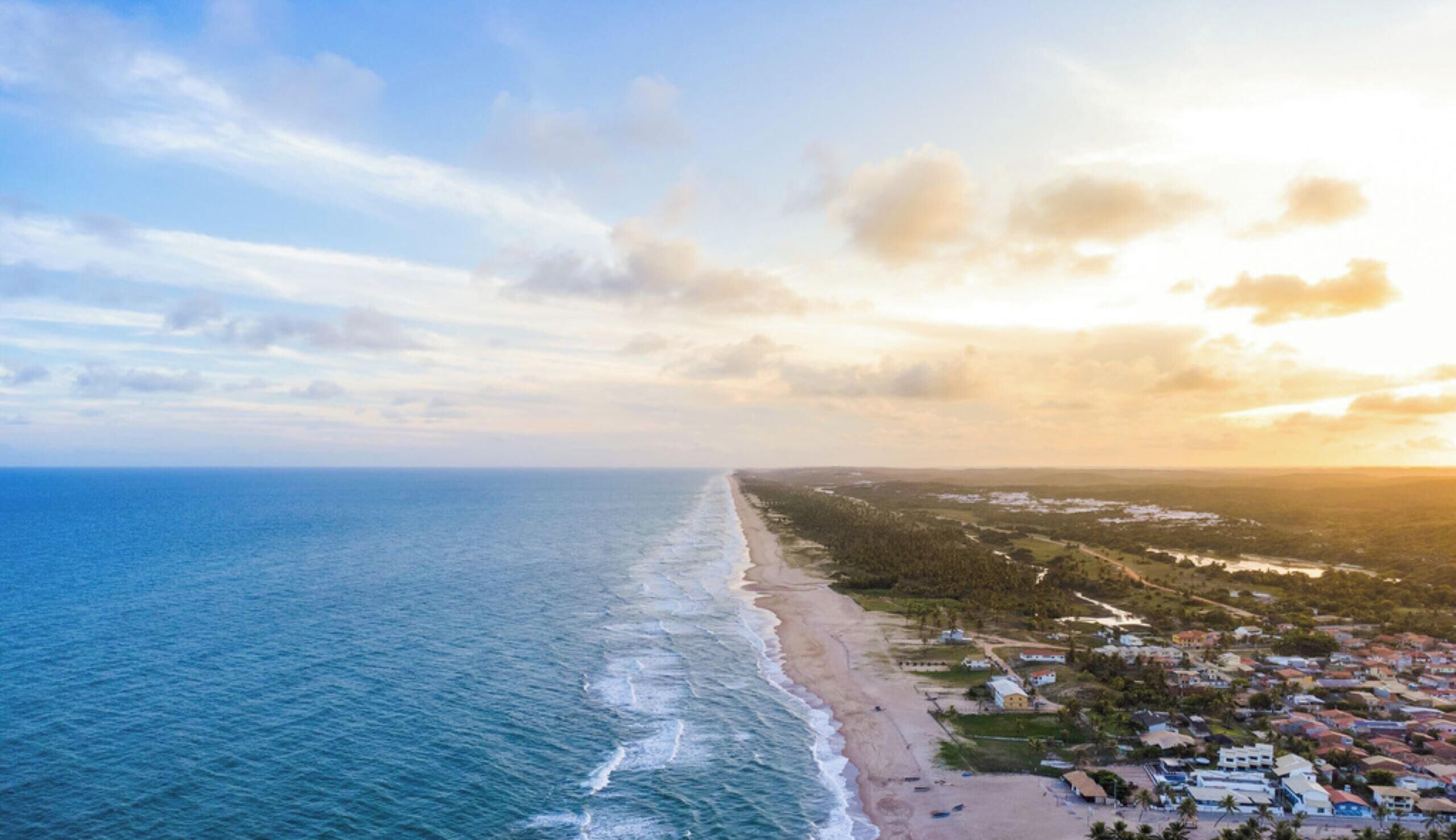 An aerial view of a coastal area with a beach and residential buildings.