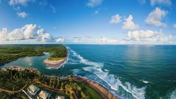 A coastal landscape with a beach, ocean, and a forested area.