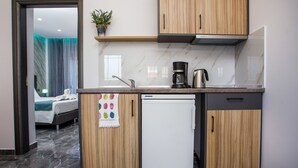 A compact kitchen with wooden cabinets, a built-in coffee maker, and a mini refrigerator. - Platoni Elite Luxury apartment (Ιαλυσός)