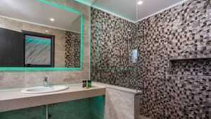 A modern bathroom with a marble sink, a glass shower enclosure, and a textured wall design. - Platoni Elite Luxury apartment (Ιαλυσός)