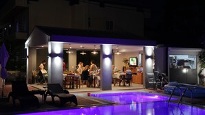 An outdoor pool area with lounge chairs, a dining area with people, and a bar. - Platoni Elite Luxury apartment (Ιαλυσός)