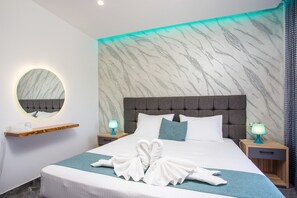Habitación de hotel con una cama grande, un espejo redondo, dos mesitas de noche con lámparas y una pared con estampado de mármol.