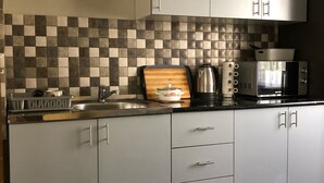 A modern kitchen with grey cabinets, a checkered backsplash, and stainless steel appliances.