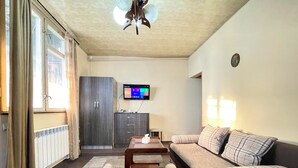 A living room with a sofa, a coffee table, and a television on the wall.