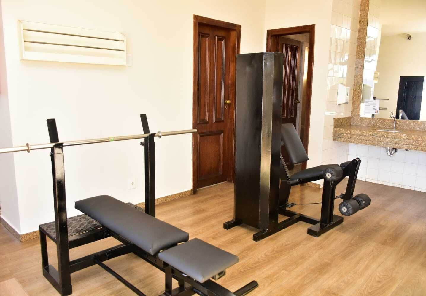 A home gym with a bench press, a squat rack, and a bench press with weights.