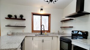 A kitchen with white cabinets, a black stove, and a window with a wooden frame. - Clean, Comfy, digs close to all the attractions (Eagan)