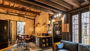 Une cuisine rustique avec des murs en briques apparentes, un plafond en bois et un coin bar avec des tabourets.