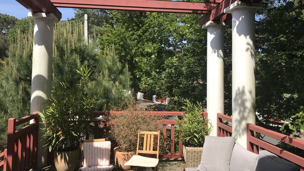 Katettu ulkotila, jossa on pergola, tuoleja ja sohva.