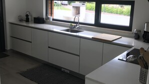 A modern kitchen with a large window, white cabinetry, and a black and white rug.