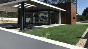 A modern house with a glass facade, a wooden exterior, and a well-maintained lawn.