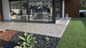 A modern house with a glass sliding door leading to a patio area.