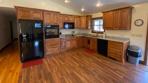 Una cocina amplia con armarios de madera, un refrigerador, un horno, un microondas y un lavavajillas.