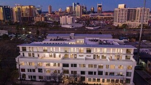 A multi-story hotel with a flat roof, large windows, and a city skyline in the background.