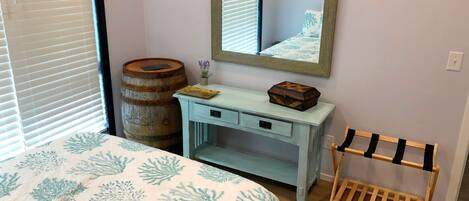 A bedroom with a bed, a dresser, a mirror, a wooden barrel, and a wooden rack.