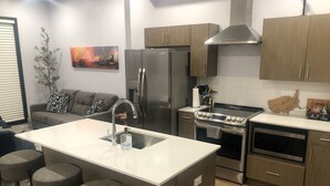 A modern kitchen with a central island, stainless steel appliances, and a bar stool seating area.