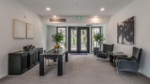 A modern lobby with a reception desk, seating area, and a large window.