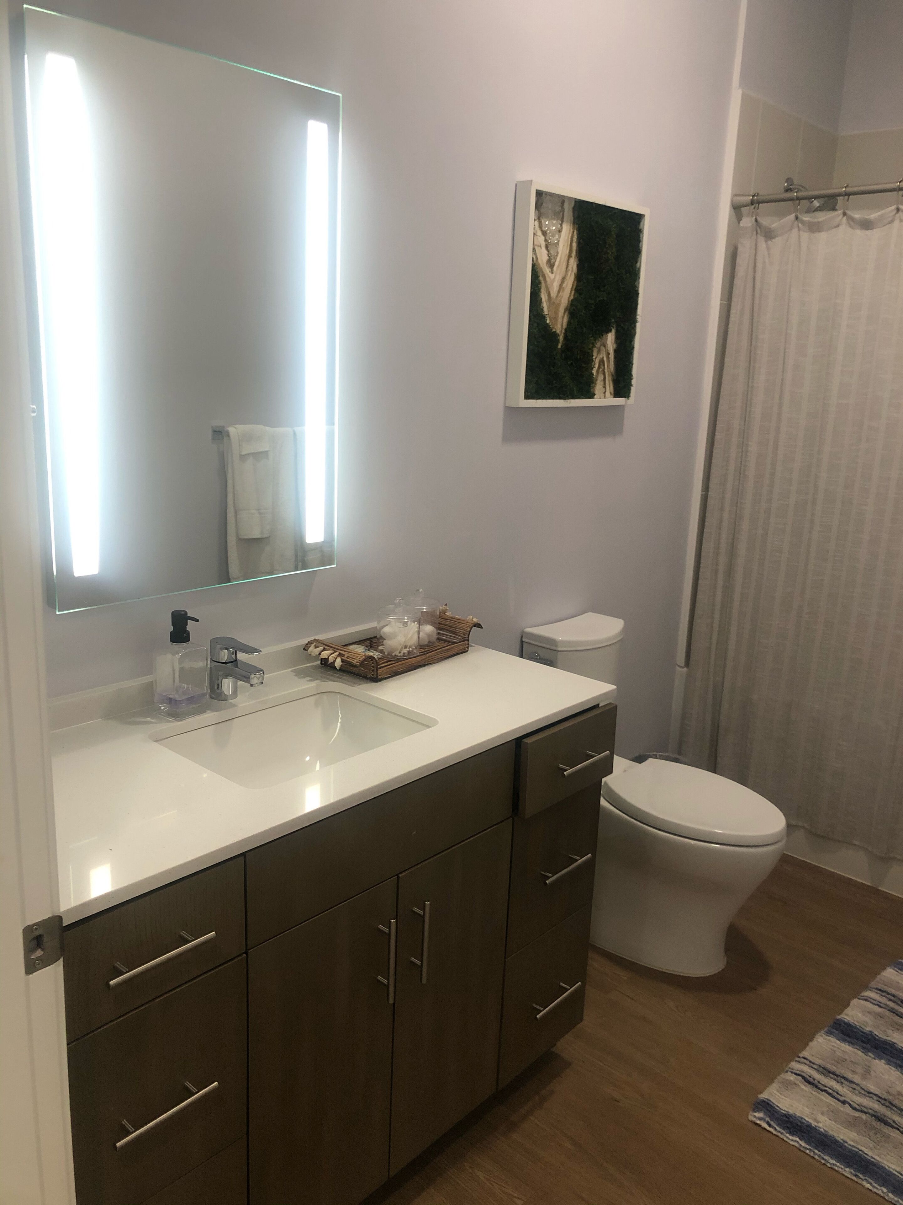 Un baño moderno con un lavamanos blanco, un espejo, un inodoro y una cortina de ducha.