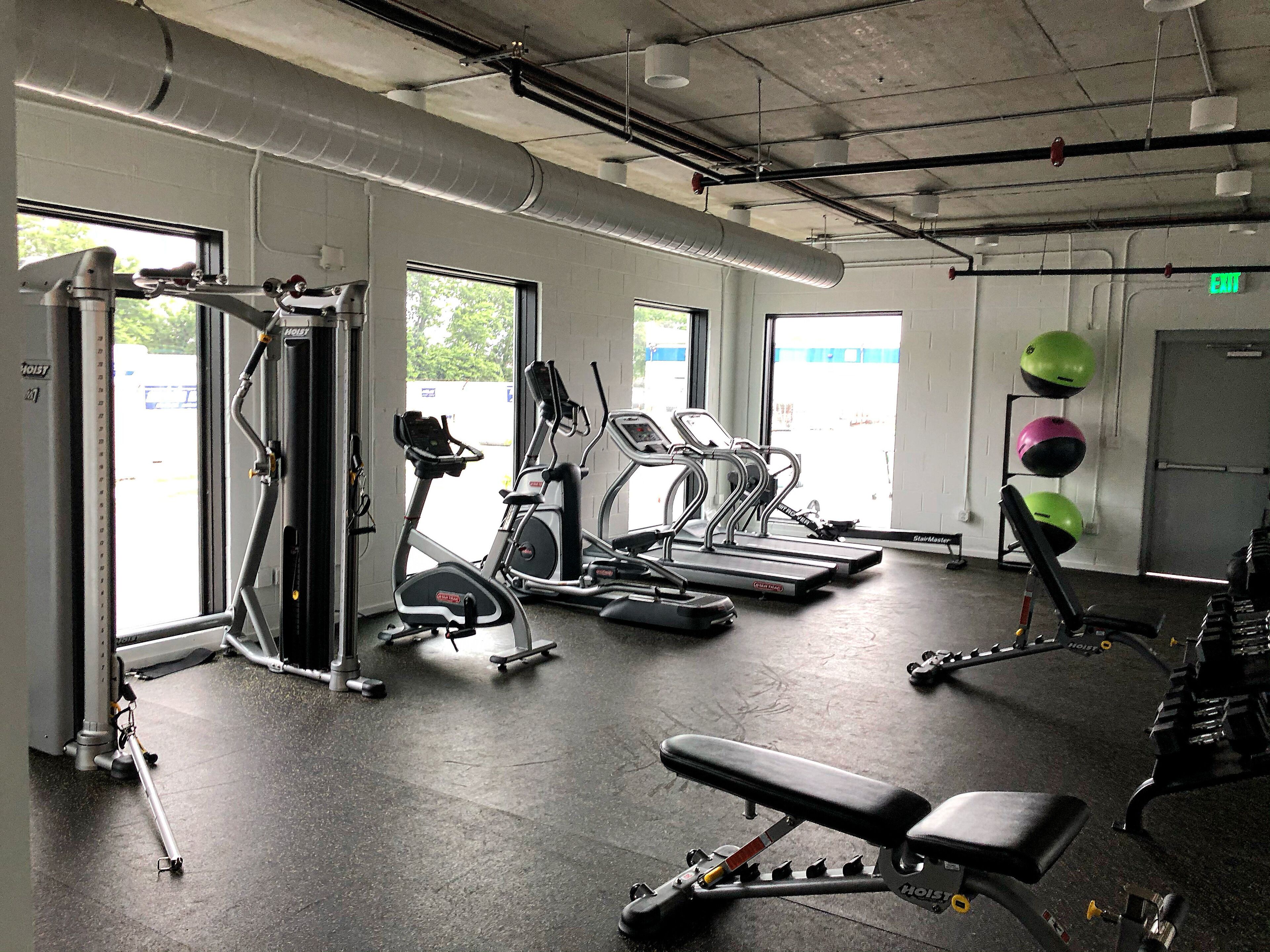 A gym with exercise equipment, a bench, and a window with a view of the outside.