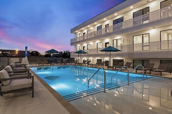 Relax by the rooftop pool, surrounded by lounge chairs and umbrellas.