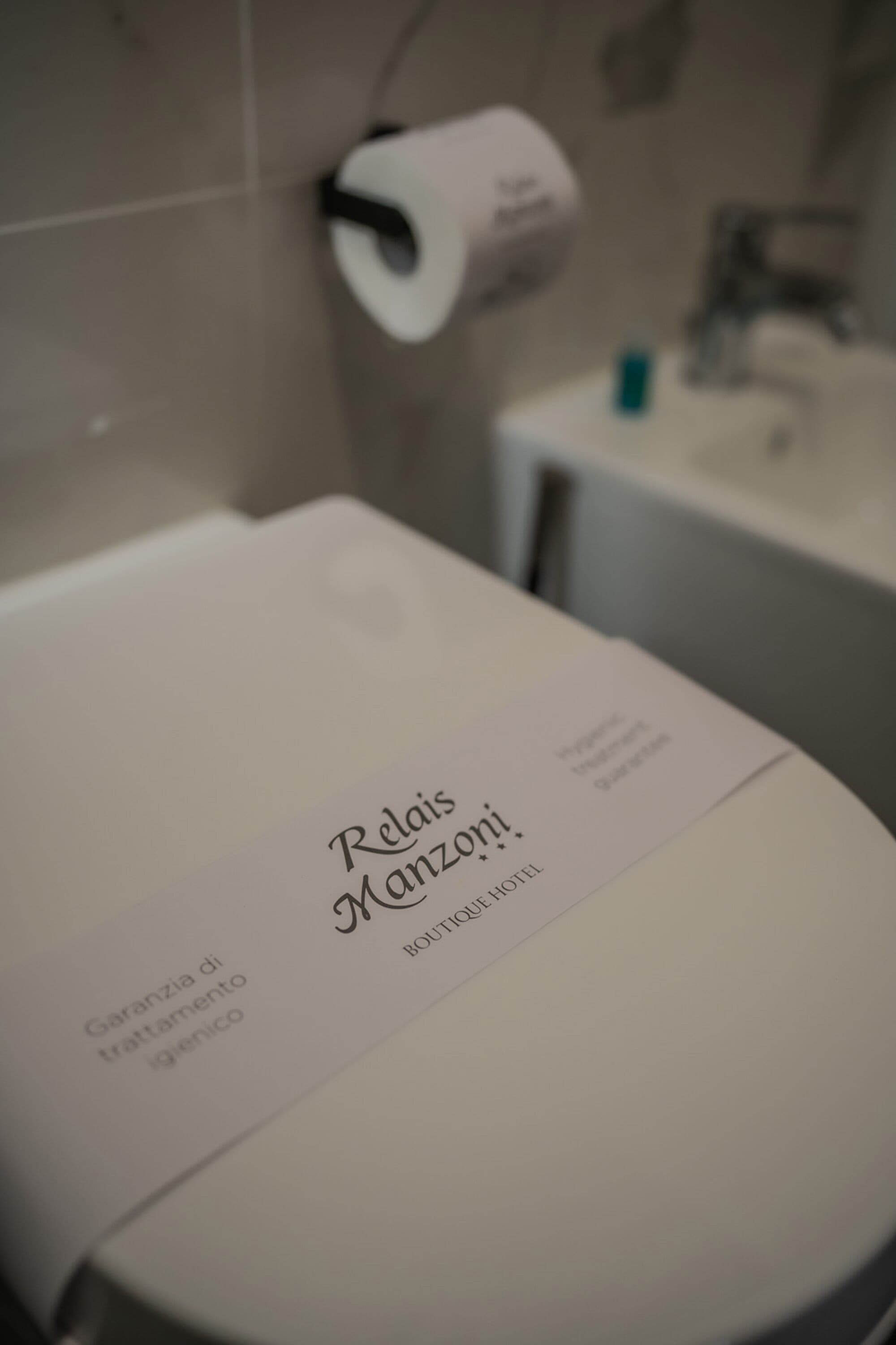 A toilet with a label that reads "Relais Manzoni" and "Guarantee di trattamento igienico."